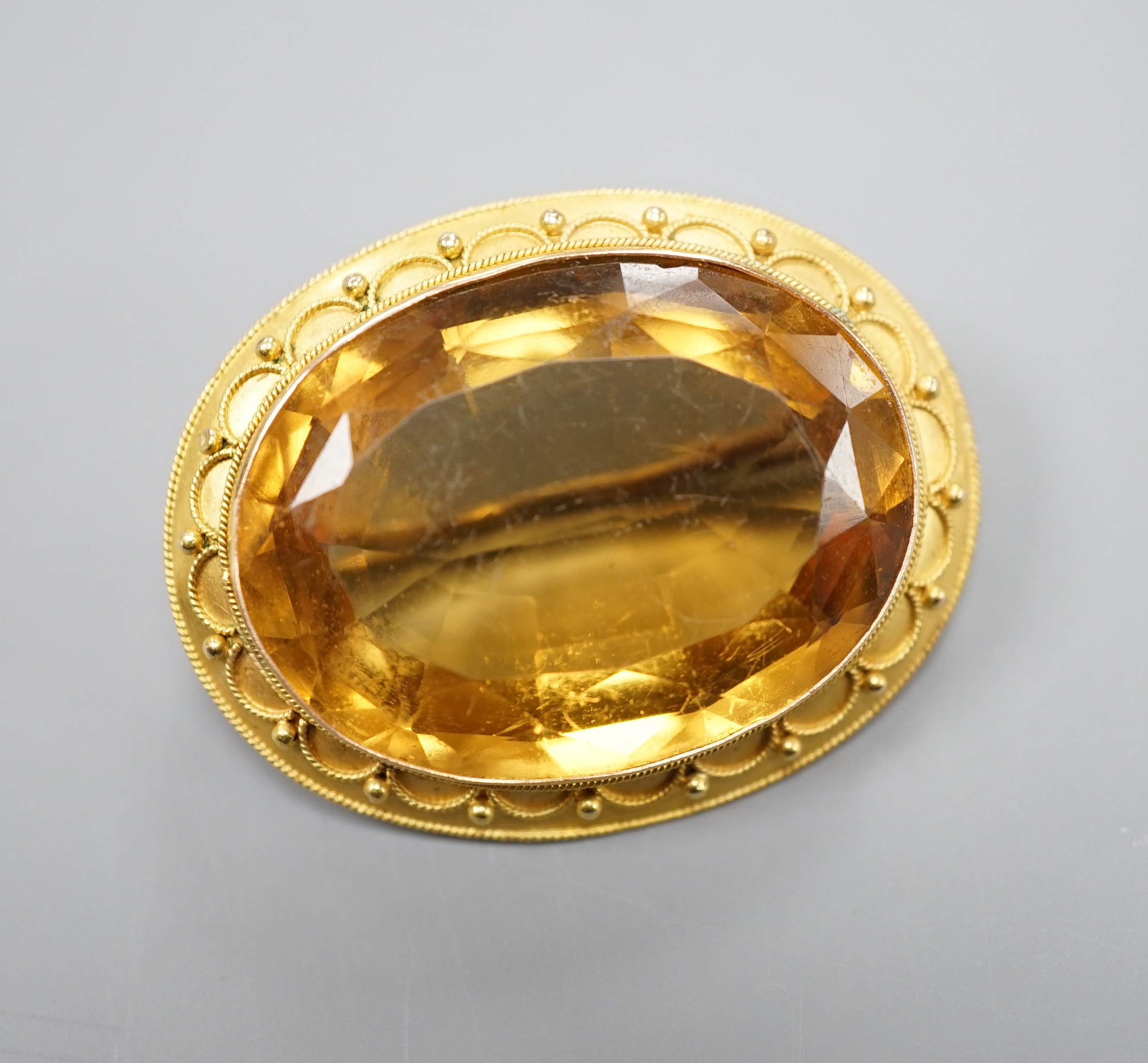A Victorian yellow metal and citrine set oval brooch, with cannetille work border, 35mm, gross weight 11.3 grams.